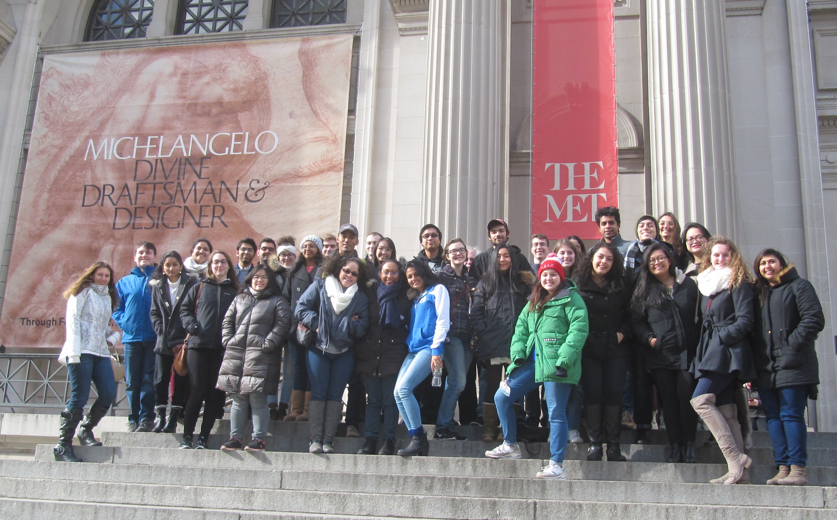 Honors College Students, COAD Students, and Staff on the steps of the museum in front of the Michelangelo poster.